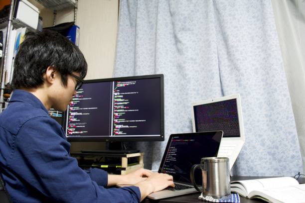 A young Asian programmer does programming in his room A young Asian programmer does programming in his room with multiple displays and drinks a cup of coffee cascading style sheets photos stock pictures, royalty-free photos & images