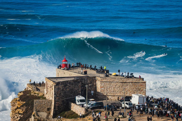 Surfer Riding Huge Wave in Nazare, Portugal, Famously Known for Having the Biggest Waves in the World. Surfer riding giant wave near the Fort of Sao Miguel Arcanjo Lighthouse in Nazare, Portugal. Nazare is famously known for having the biggest waves in the world. Biggest stock pictures, royalty-free photos & images