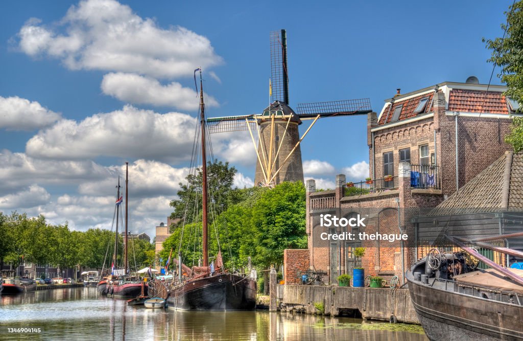 Windmill in Gouda, Holland Windmill and historical boats in a canal in Gouda, Holland Gouda - South Holland Stock Photo
