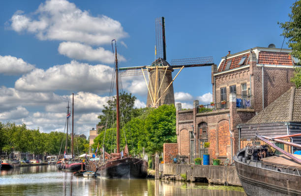 Windmill in Gouda, Holland Windmill and historical boats in a canal in Gouda, Holland gouda south holland stock pictures, royalty-free photos & images