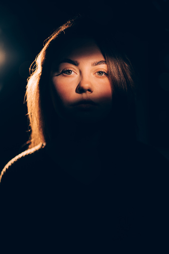 lady portrait focus on face in soft warm light shadow contrast isolated on dark free space background.