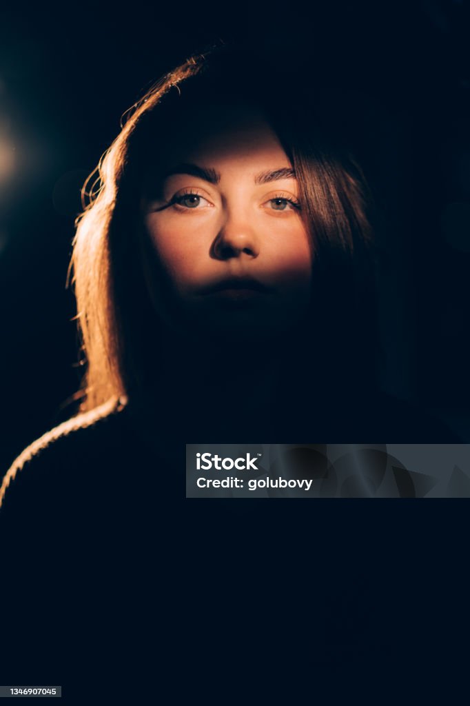 woman lady portrait focus on face in soft warm light shadow contrast isolated on dark free space background. Violence Stock Photo