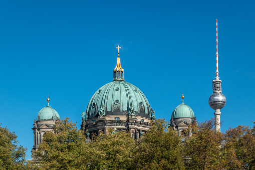 Berlin Cathedral (Germany) with the television tower on Alexander Platz in the background. \nThe history of the Berlin Cathedral goes back to the 15th century. The predecessor buildings were originally part of the Berlin City Palace. In the early nineteenth century, Prussia’s leading architect Karl Friedrich Schinkel transformed the court church into a neo-classical building.