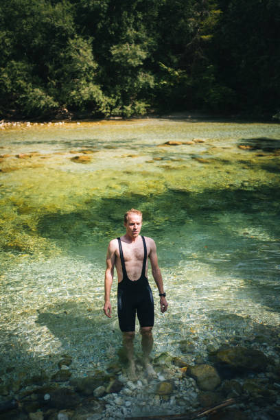 istock Cyclist walks down to river after ride, in summer 1346908347