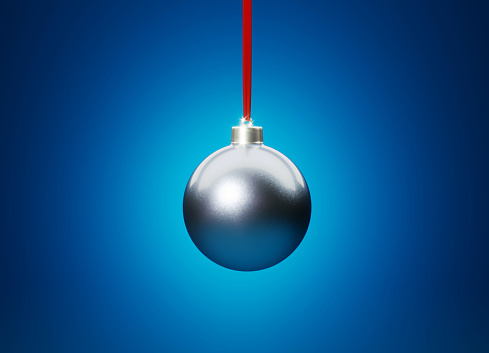 Blue Christmas bauble hanging over blue background. Christmas and festivity concept. Horizontal composition with selective focus and copy space.