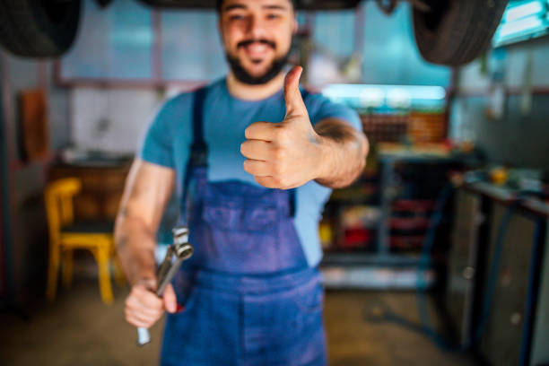 Car mechanic with thumb up Young happy car mechanic with thumb up in auto repair shop car portrait men expertise stock pictures, royalty-free photos & images