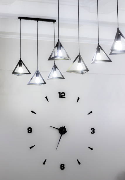 istock Minimalistic design of a wall clock with black numbers and a light bulb 1346926374