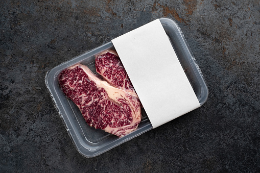 Raw Striploin marbled beef steak in vacuum packaging, logo mockup