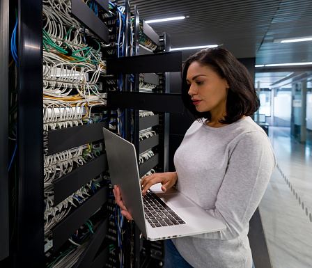 Latin American female computer engineer fixing a network server at an office - technology concepts