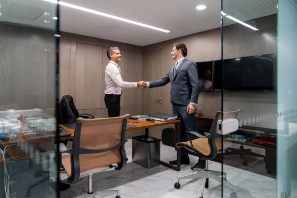 Business men in a meeting closing a deal with a handshake Successful business men in a meeting at the office and closing a deal with a handshake office leave stock pictures, royalty-free photos & images