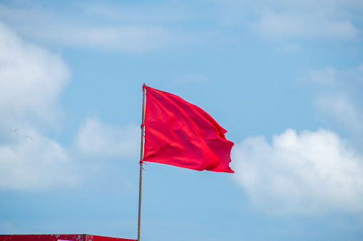 Red flag on the beach as warning for tourists for don't swim.