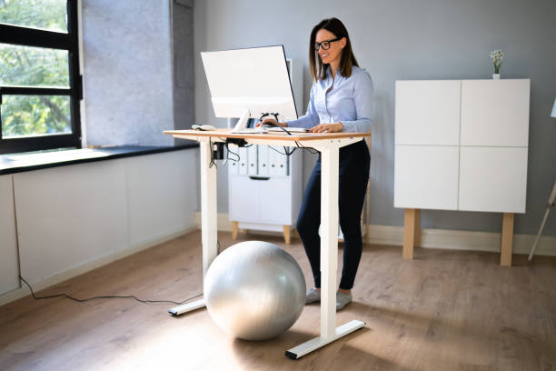 istock Woman Using Adjustable Height Standing Desk In Office 1346931515