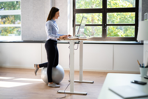 Mujer que usa un escritorio de pie de altura ajustable en la oficina photo