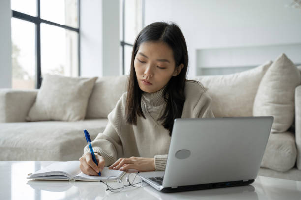 istock A young Asian female student is using a computer and a tablet. A young business woman is sitting at a desk and taking notes in a notebook. The concept of education and technology 1346938740