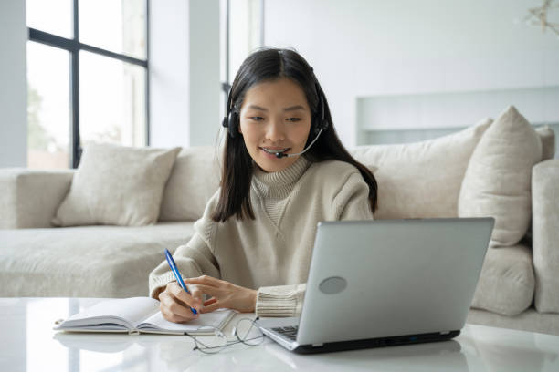 istock An Asian woman using a headset looks at the laptop screen, communicates with the interlocutor. Korean business woman with headphones video call for customer service 1346938920