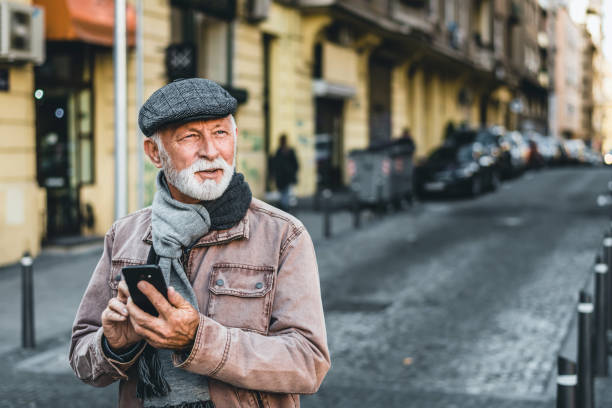 istock Smiling mature man using smartphone, standing on the street. Mobile banking concept. 1346939768