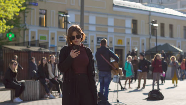 A woman in sunglasses and a phone in her hands stock photo