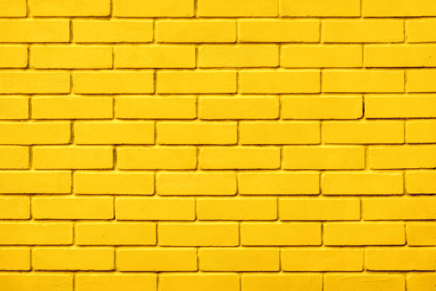 istock Painted bricks design yellow color wall background blocks. Natural design texture background yellow brick wall color paint block pattern. Block texture yellow painted wall brick background warm color 1346945822