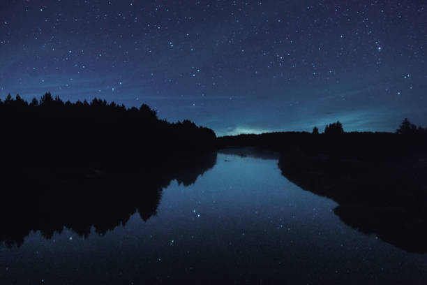 istock Night starry sky over the forest and the river 1346946979