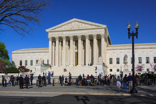 U.S. Supreme Court Building with Activists and Sightseeing Tourists in Front of the Court, Washington DC, USA. Clear Blue sky is in background. Canon EF 24-105mm/4L IS USM Lens.\n.