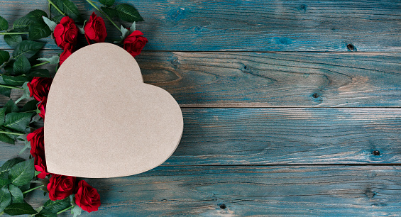 Valentines day holiday background with lovely red roses and heart shaped gift box on faded blue wooden planks