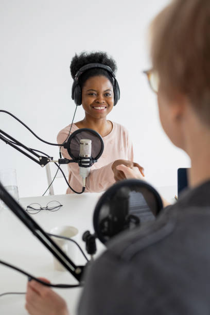 registra un podcast e crea contenuti audio. una donna afroamericana suona l'ukulele in uno studio di registrazione o alla radio - mid adult audio foto e immagini stock