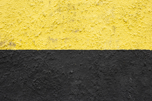 A yellow and black painted wall. divided in two parts by a horizontal line. urban background. copy space. industrial style.