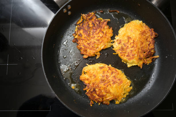 golden roasted vegetable fritters from potato and red kuri squash in a black pan, also called pumpkin rosti or autumn pancake, copy space, high angle view from above - latke imagens e fotografias de stock