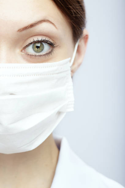 istock Female doctor wearing protective  face mask against light blue background 1346952315
