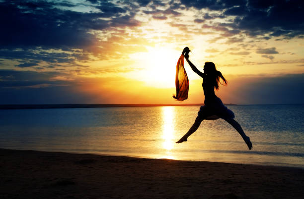 istock Jumping woman at the summer beach during sunset 1346953423