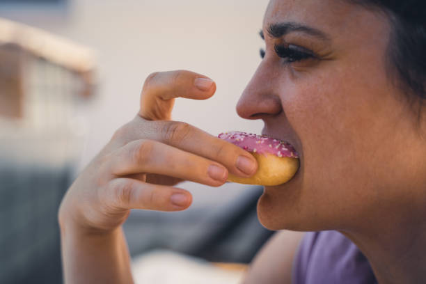 istock Young woman bites into a pink donut 1346956743