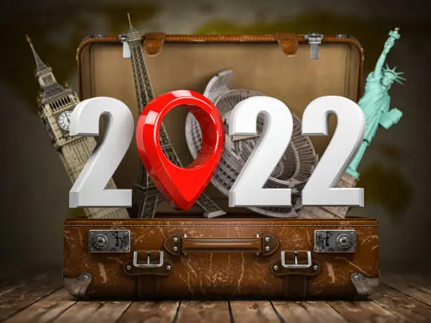 Photo of 2022 Happy new year. Number 2022 and pin with most popular landmarks of the world in vintage suitcase.