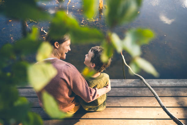 Mother and son relaxing at a lake stock photo