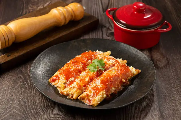 Pancakes stuffed with minced meat and topped with tomato sauce and grated cheese.