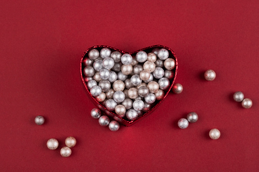 Heart box with small polystyrene balls on red background
