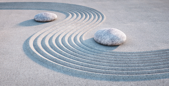 Japanese Zen garden with white stones in white textured raked sand with lines
