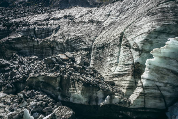 istock Nature background with icefall near glacier with cracks and scratches. Natural backdrop with icy wall and moraines. Beautiful landscape with shiny glacial wall and stones in sunlight. Glacier texture. 1346977207