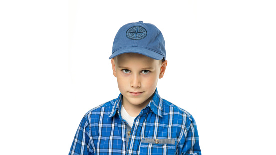 Portrait of a smiling boy in a shirt and baseball cap isolated on a white background