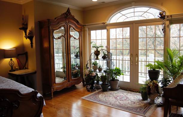 Armoire and Houseplants A bedroom with French doors out to a balcony, antique armoire, and houseplants. french doors stock pictures, royalty-free photos & images