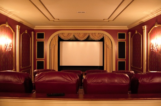 A home movie theater room with screen, seats, and décor.