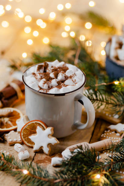 istock Winter hot drink: white mug with hot chocolate with marshmallow and cinnamon. Cozy home atmosphere, festive holiday mood. Rustic style, wooden background. Homemade gingerbread cookies, dry orange 1346999524