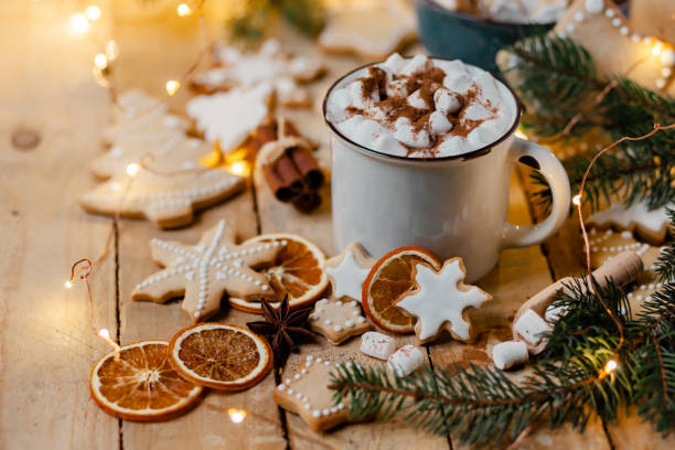 istock Winter hot drink: white mug with hot chocolate with marshmallow and cinnamon. Cozy home atmosphere, festive holiday mood. Rustic style, wooden background. Homemade gingerbread cookies, dry orange 1346999536