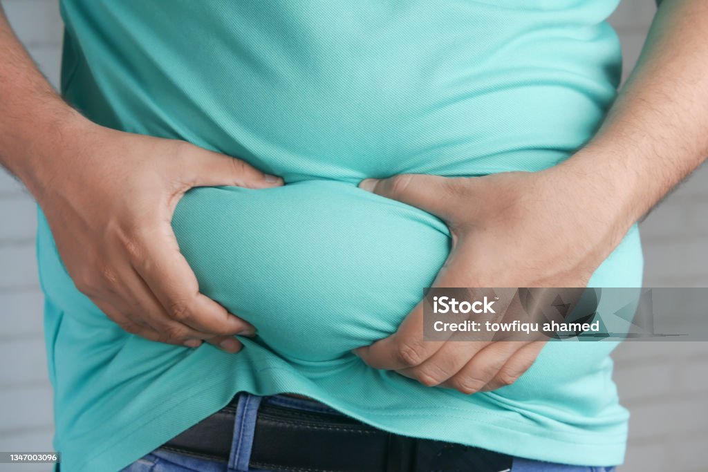 man's hand holding excessive belly fat, overweight concept man's hand holding excessive belly fat, overweight concept. Obesity Stock Photo