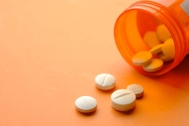 istock white color medical pills spilling on orange background 1347003203