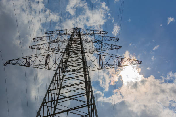 Power pole and power lines with blue sky and first thunderclouds in the background