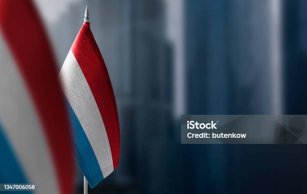Small Flags Of Luxembourg On A Blurry Background Of The City Stock Photo - Download Image Now