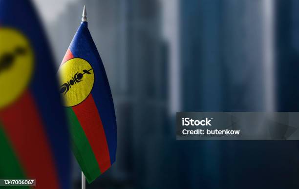 Small Flags Of New Caledonia On A Blurry Background Of The City Stock Photo - Download Image Now