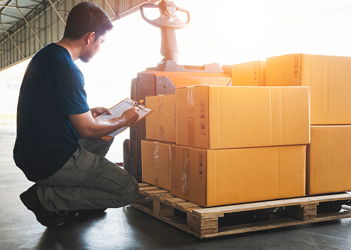 Asian Warehouse Worker Holding Clipboard His Doing Inventory Management. Cargo Shipment Check Stock Package Boxes.