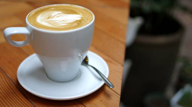 istock Latte art rosetta pattern tulip shape in white coffee cup with ceramic plate and stainless steel spoon on wooden table 1347009291