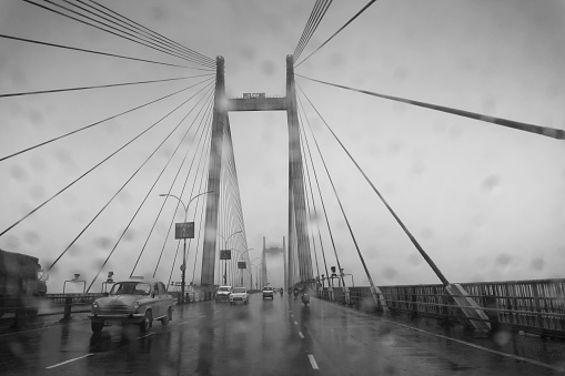 Howrah, West Bengal, India - 25th September 2019 : Image shot through raindrops falling on car windshield , wet glass, traffic at 2nd Hoogly bridge. Monsoon black and white stock image.